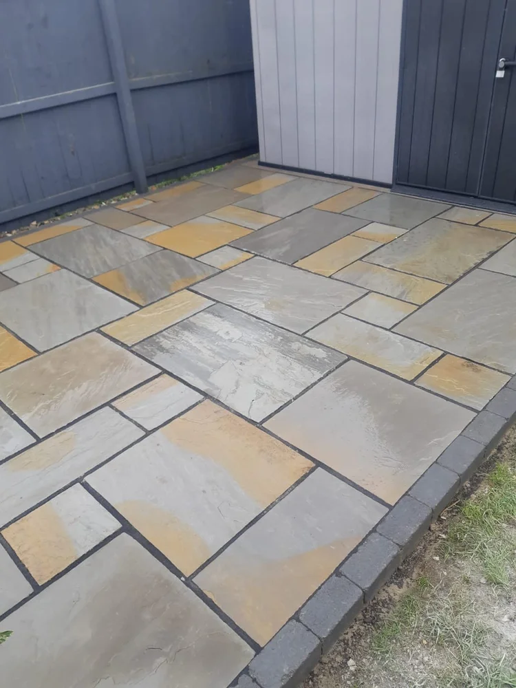 Indian sandstone patio with a charcoal kerb edge