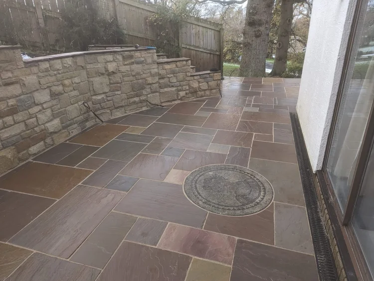 Sandstone patio with a compass feature beside a stone wall