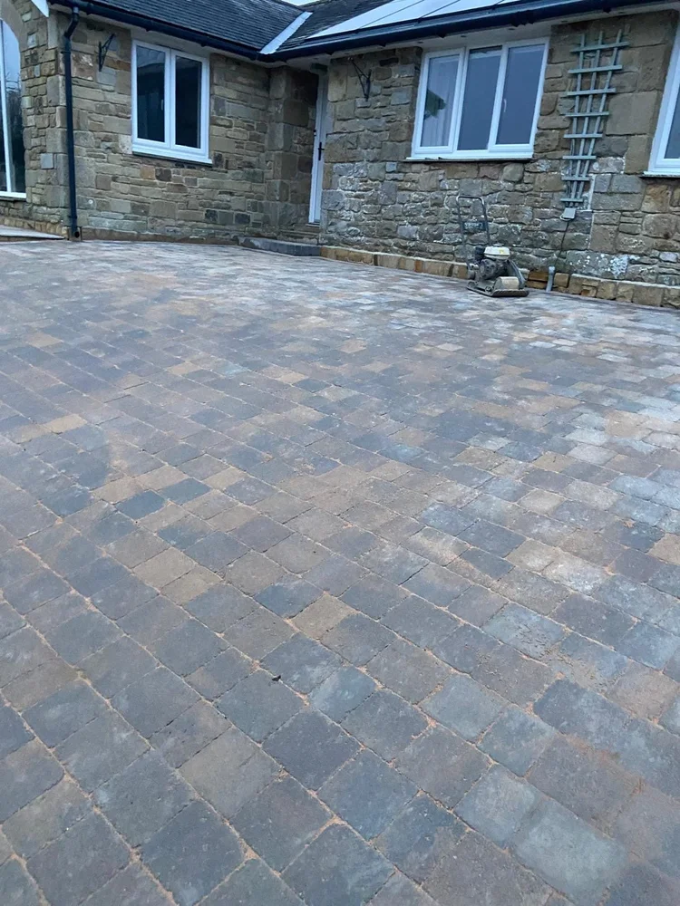Multi-tone block paving in front of a stone bungalow