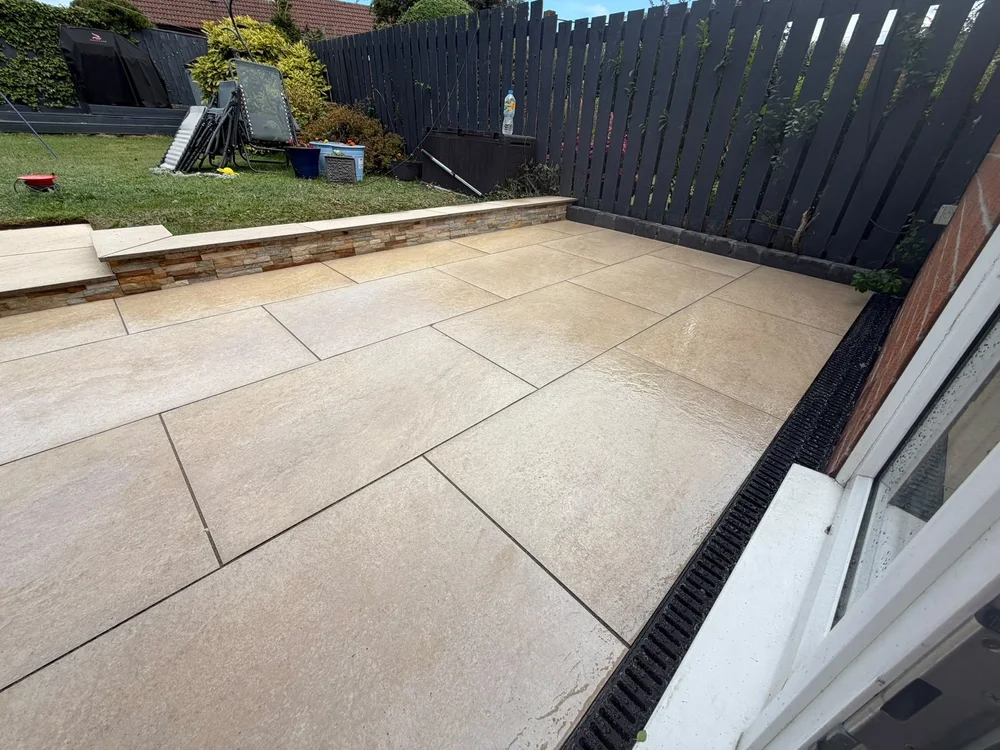 Large-format buff porcelain patio with a drainage channel