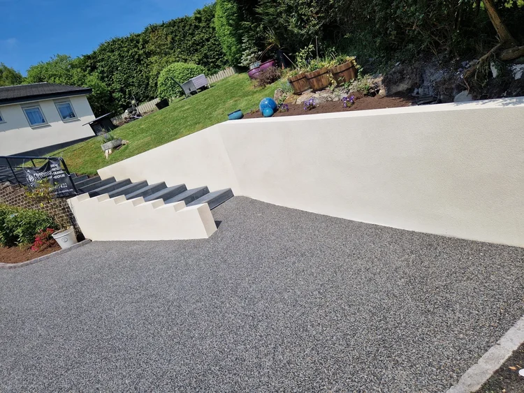 Resin driveway beside a rendered retaining wall and steps