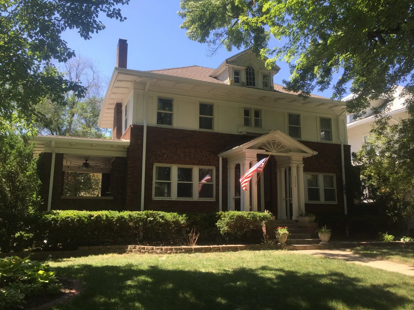 White seamless gutters and downspouts on a brick foursquare home