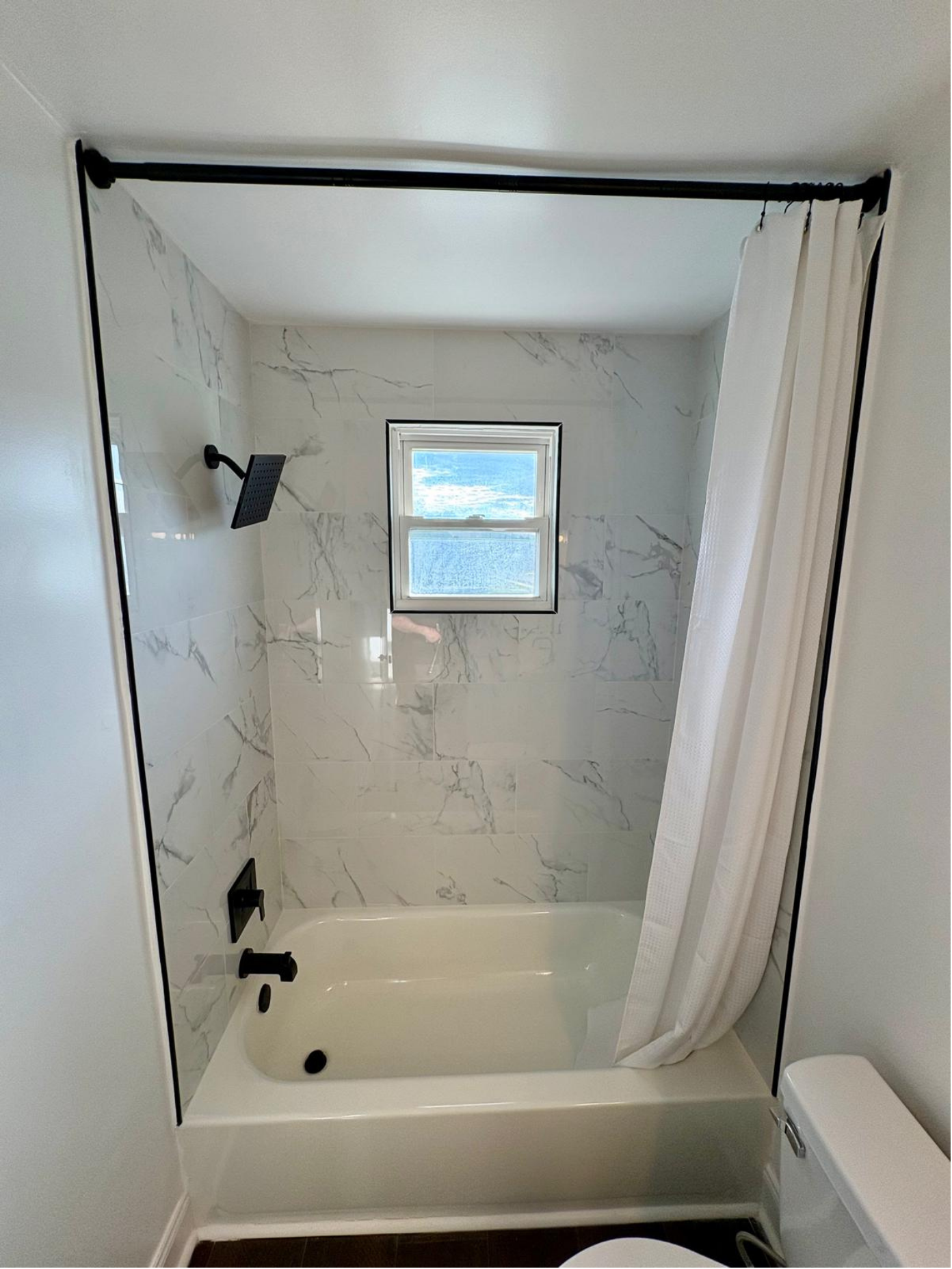 Bathroom with a window, subway tile walls, black fixtures, and a shower curtain.