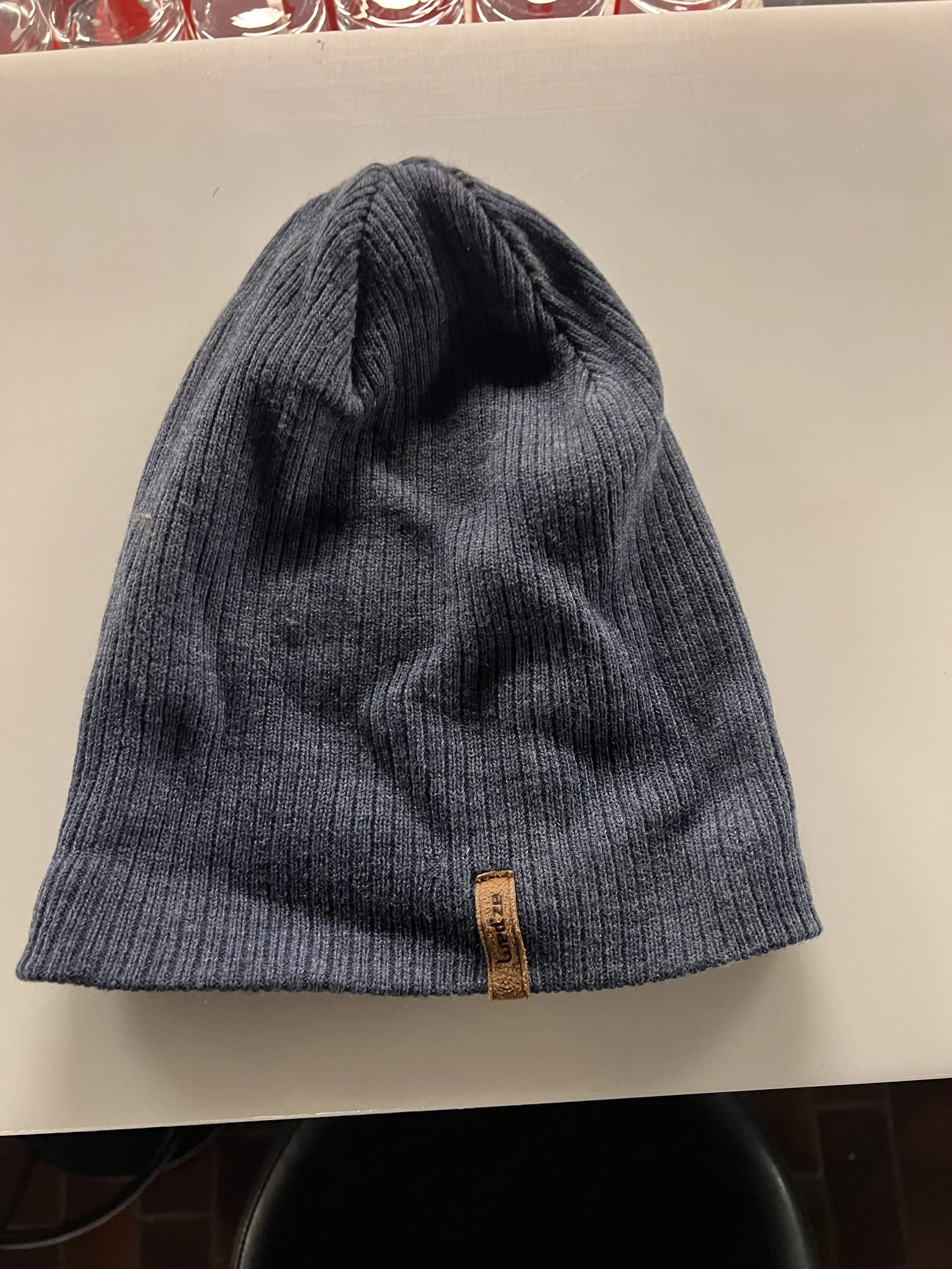 Ein grauer Strickmütze mit braunem Lederetikett.