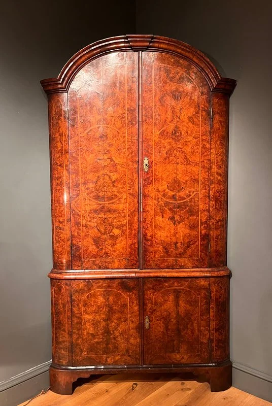 A standing George II corner cupboard veneered in burr walnut