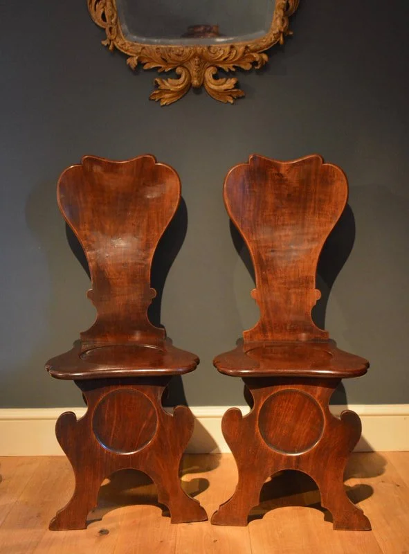 A fine pair of mahogany hall chairs of Scabello form with dished backs