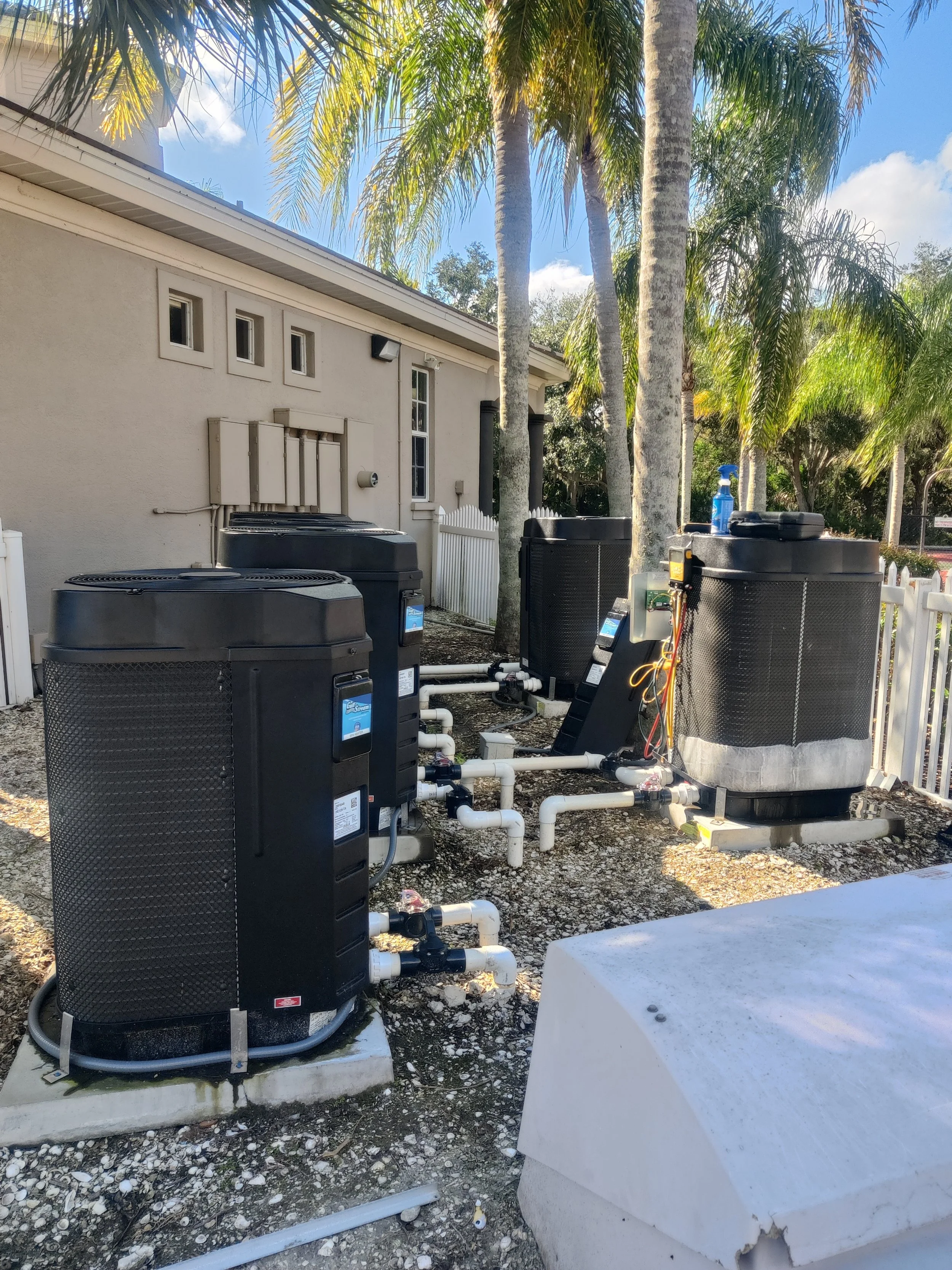 Large Commercial pool heating setup with 5 pool heaters and one being serviced.