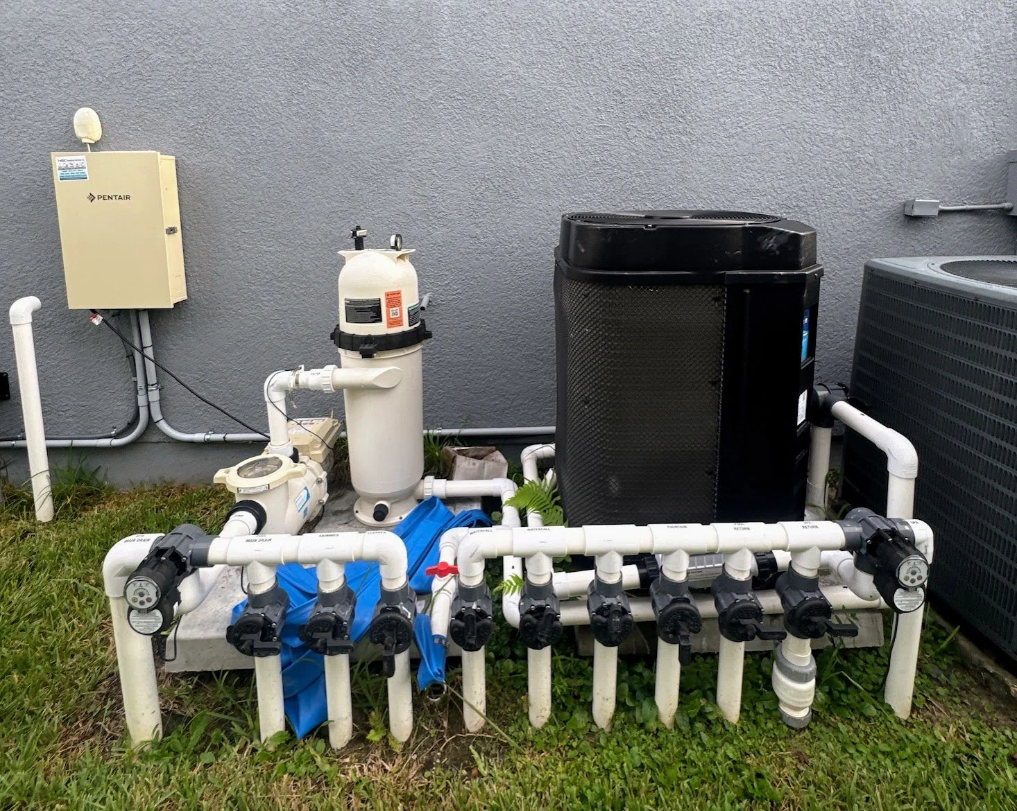 Complicated Outdoor Pool equipment pad including: Pool pump, automation system, Heat Pump Pool Heater, Filter, and various valves.