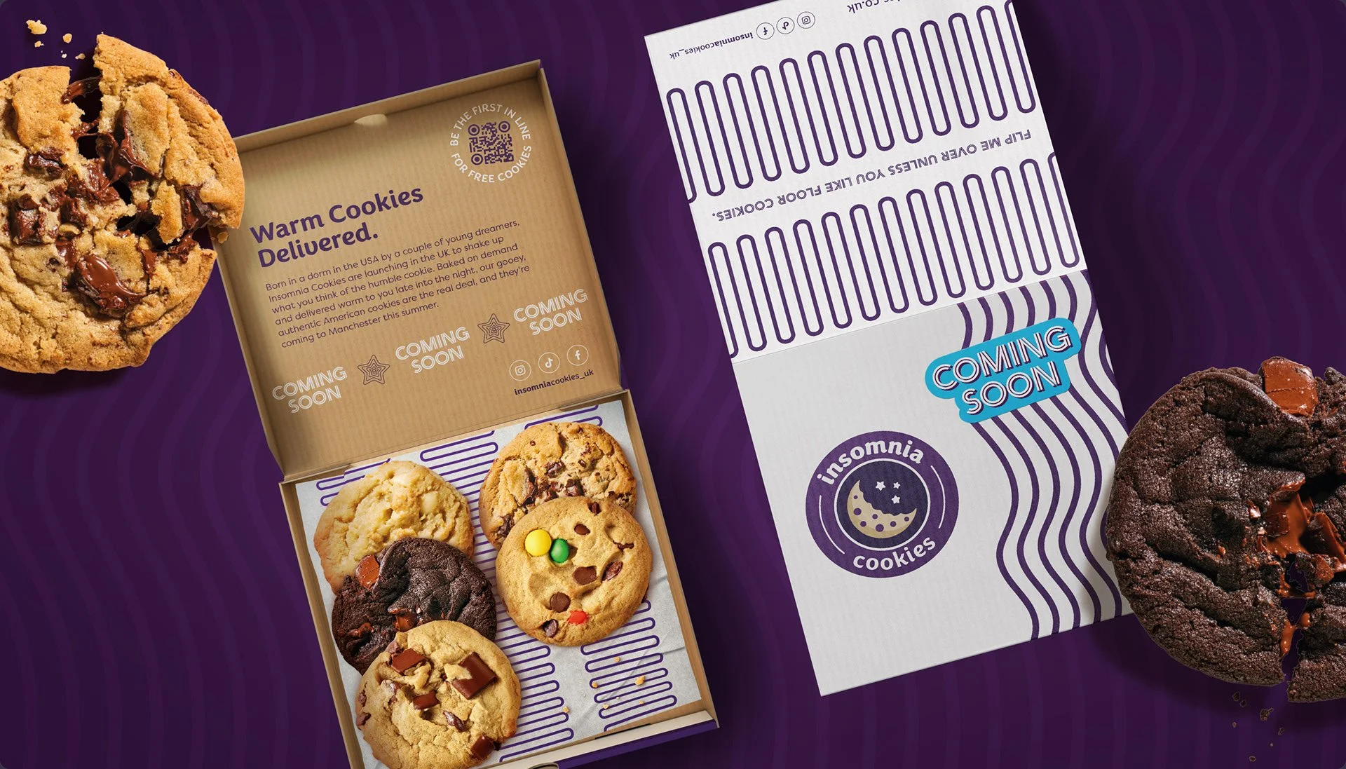 A box of assorted cookies from Insomnia Cookies, with some cookies outside the box and a purple and white Insomnia Cookies branded packaging in the background.