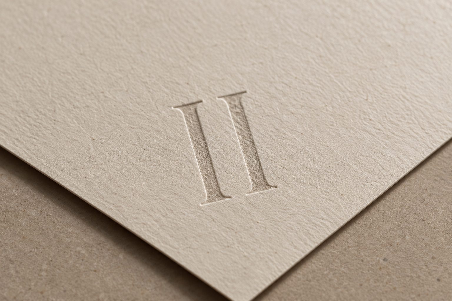 Close-up of textured cream-colored paper with an embossed Roman numeral II.