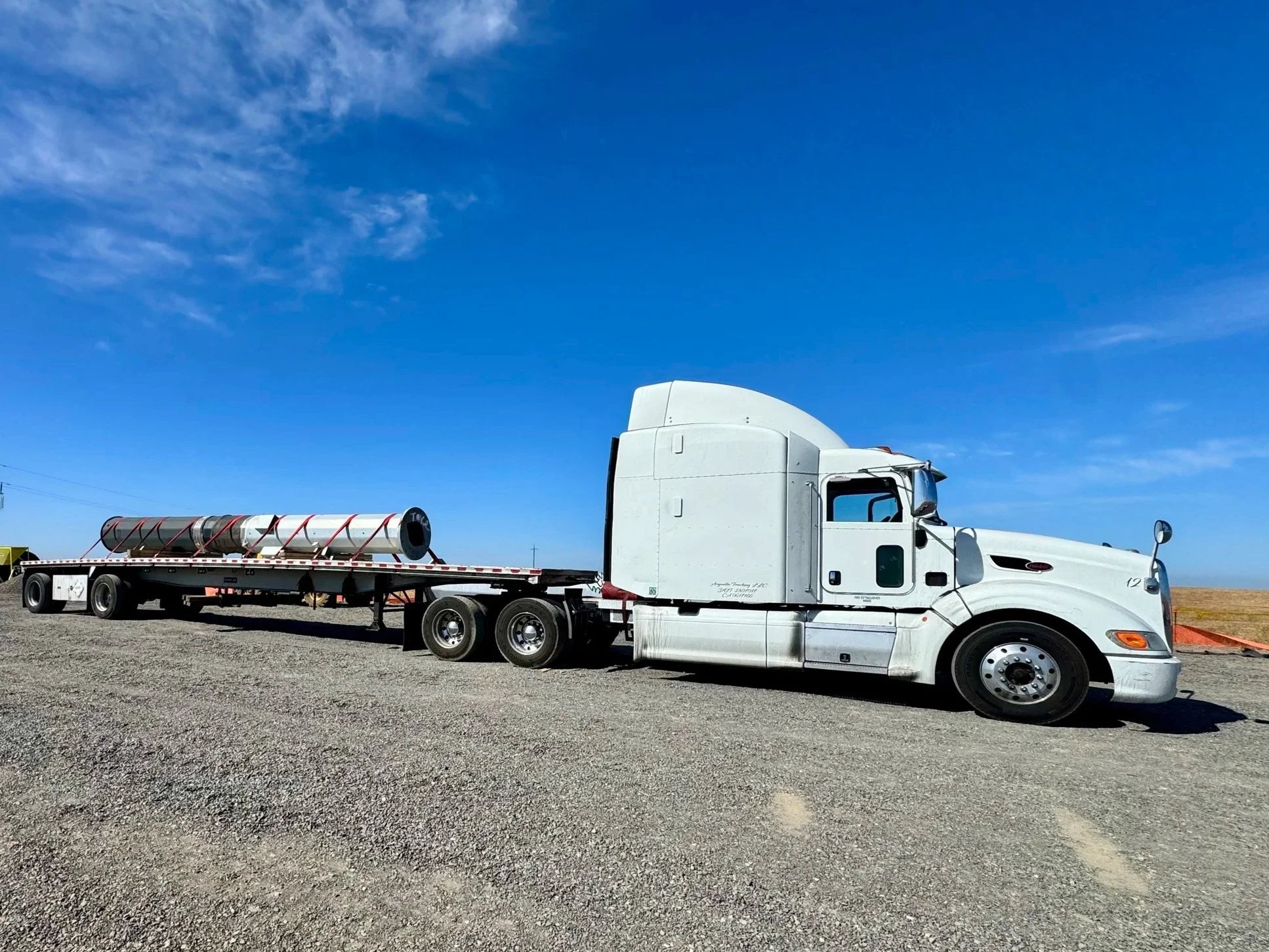 Arguello Trucking Peterbilt hauling metal pipe on a 48-foot flatbed trailer.