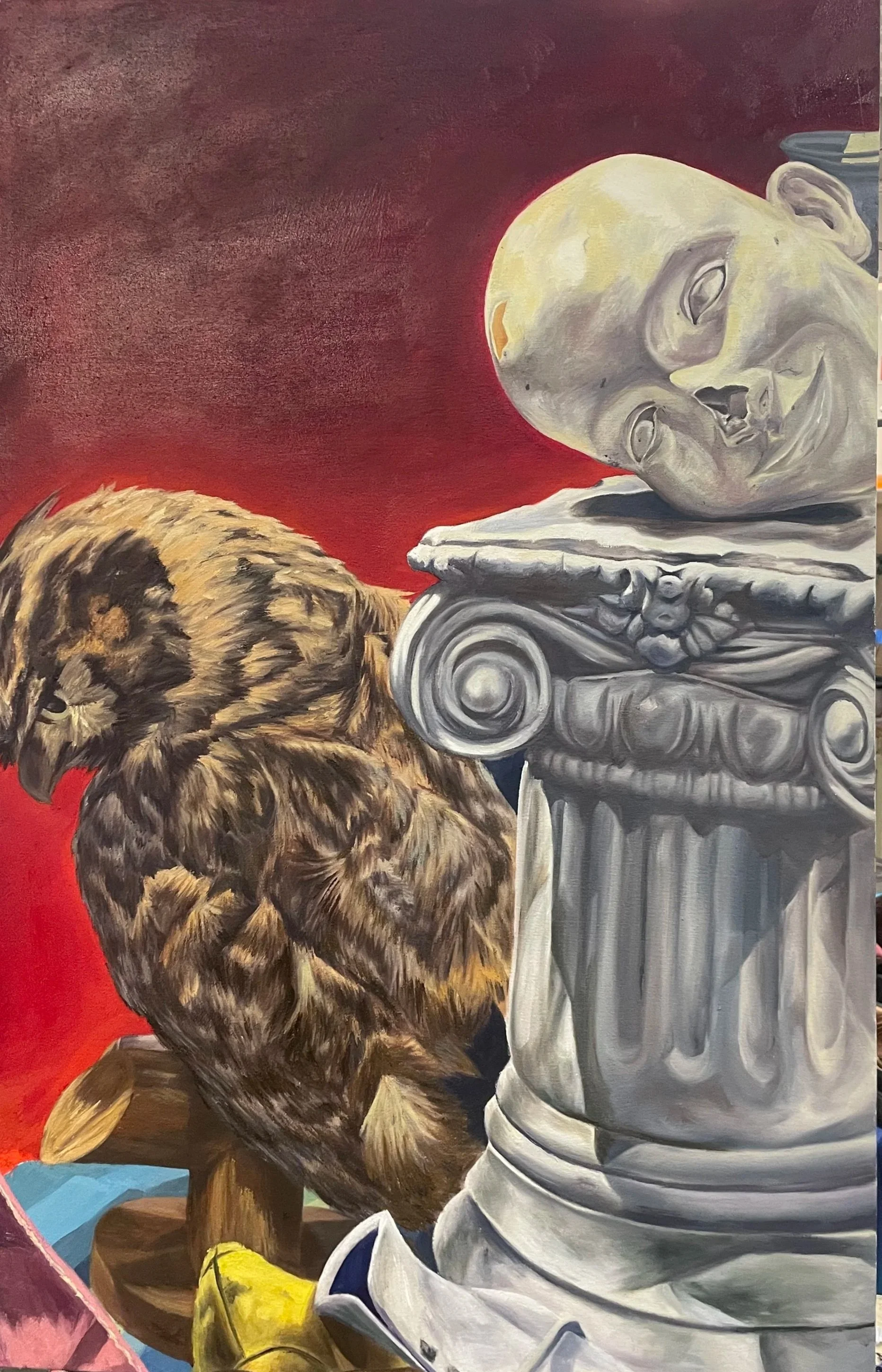 Large oil painting of a brown owl beside a pale sculpted human head resting sideways on an ornate classical column, with a dramatic deep red background and colorful objects along the bottom edge.