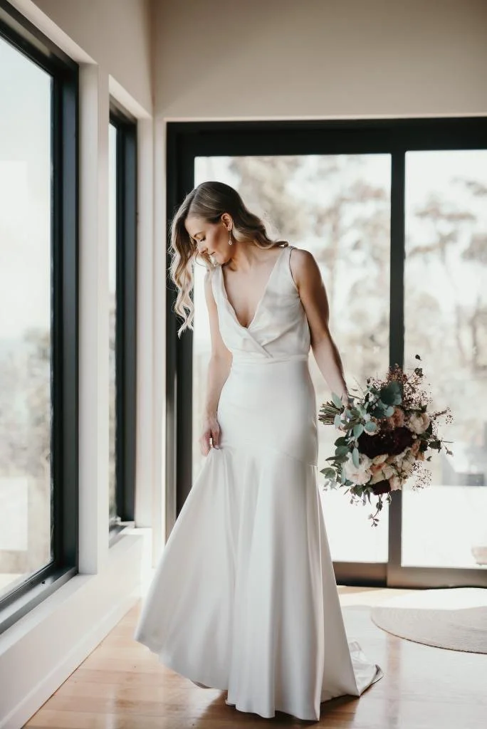 Bride in her wedding dress holding her bouquet after having her bridal makeup complete.