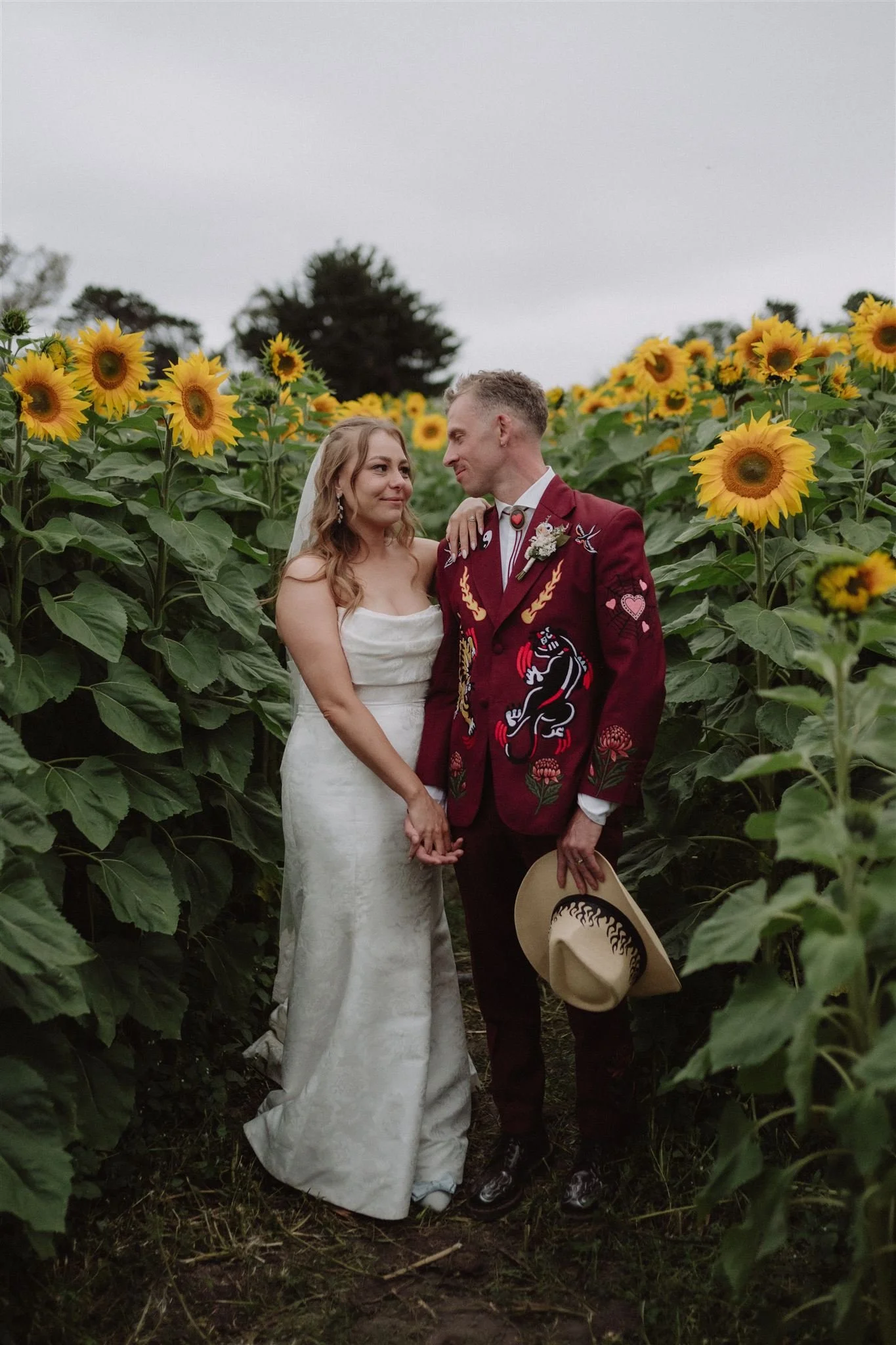 Bride and groom together in a sunflower field on their wedding day.