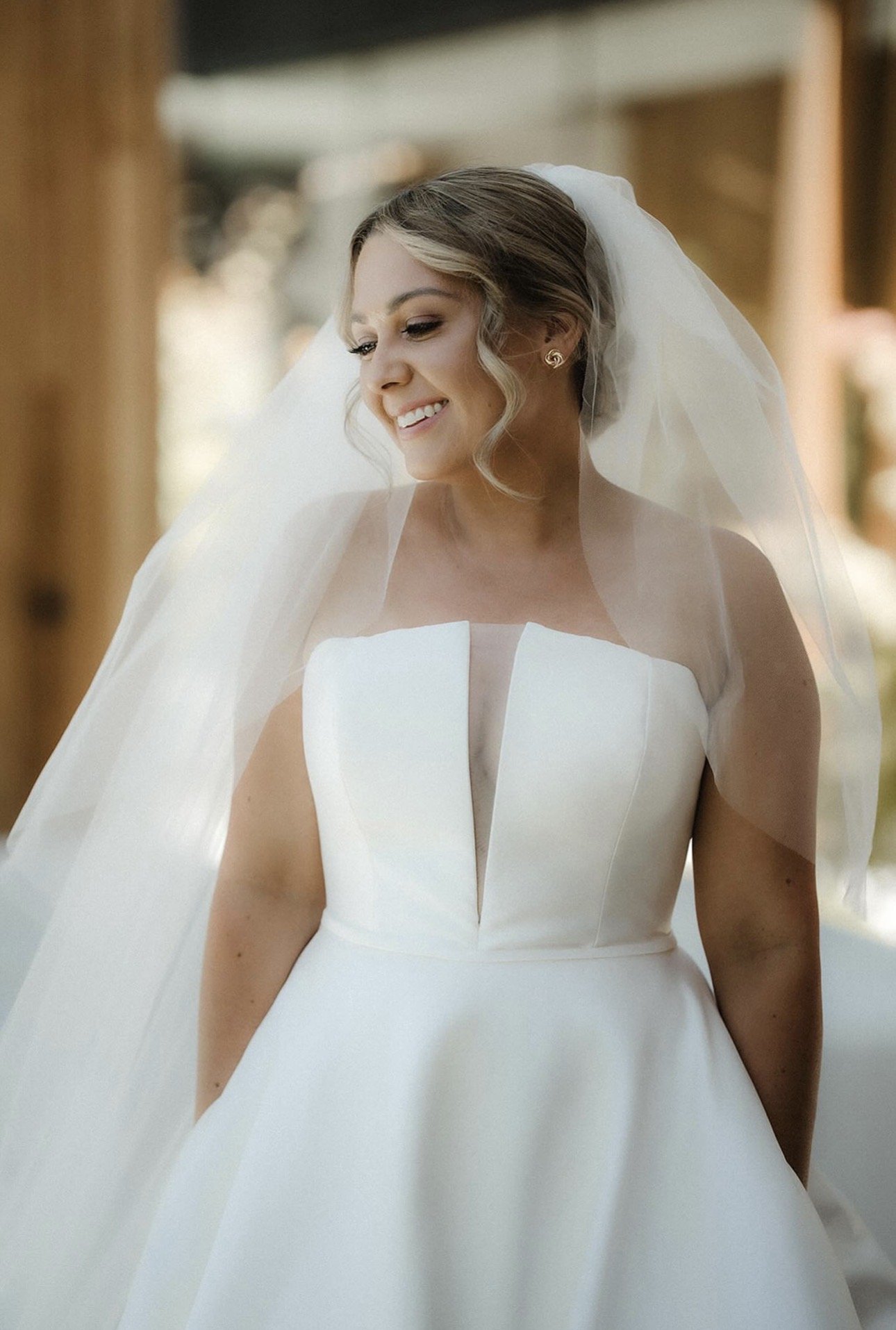 Bride wearing soft, elegant bridal makeup with pearl earrings and a veil. 