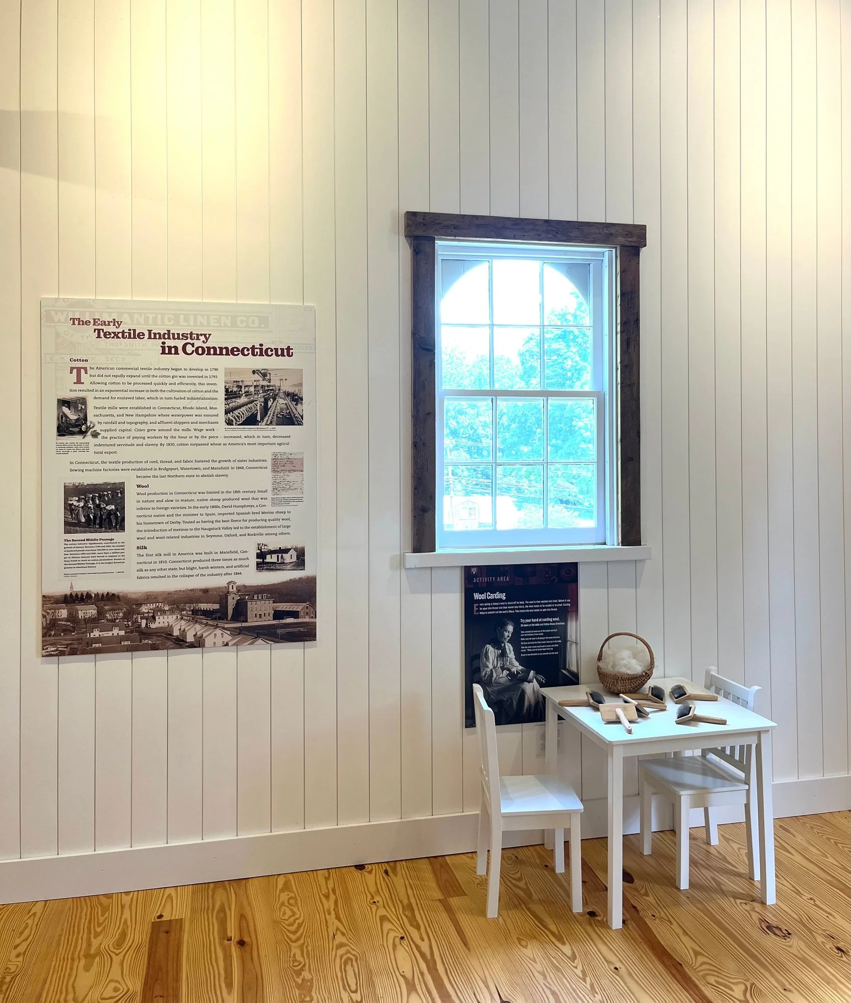 The wool carding station beside a panel on Connecticut's early textile industry.