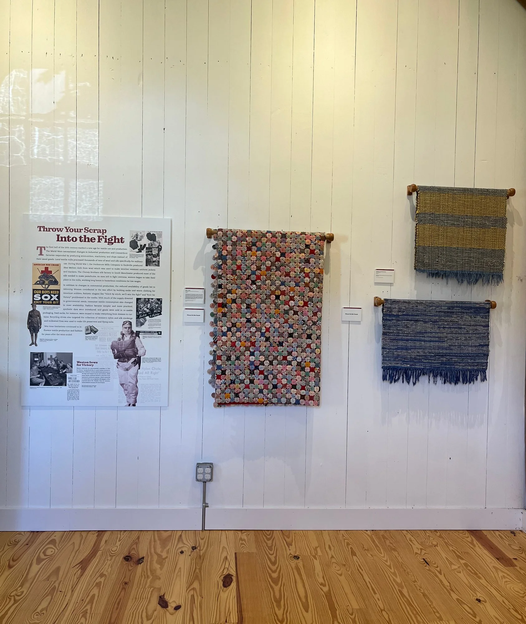 Woven and rag rugs beside a panel on wartime scrap drives.