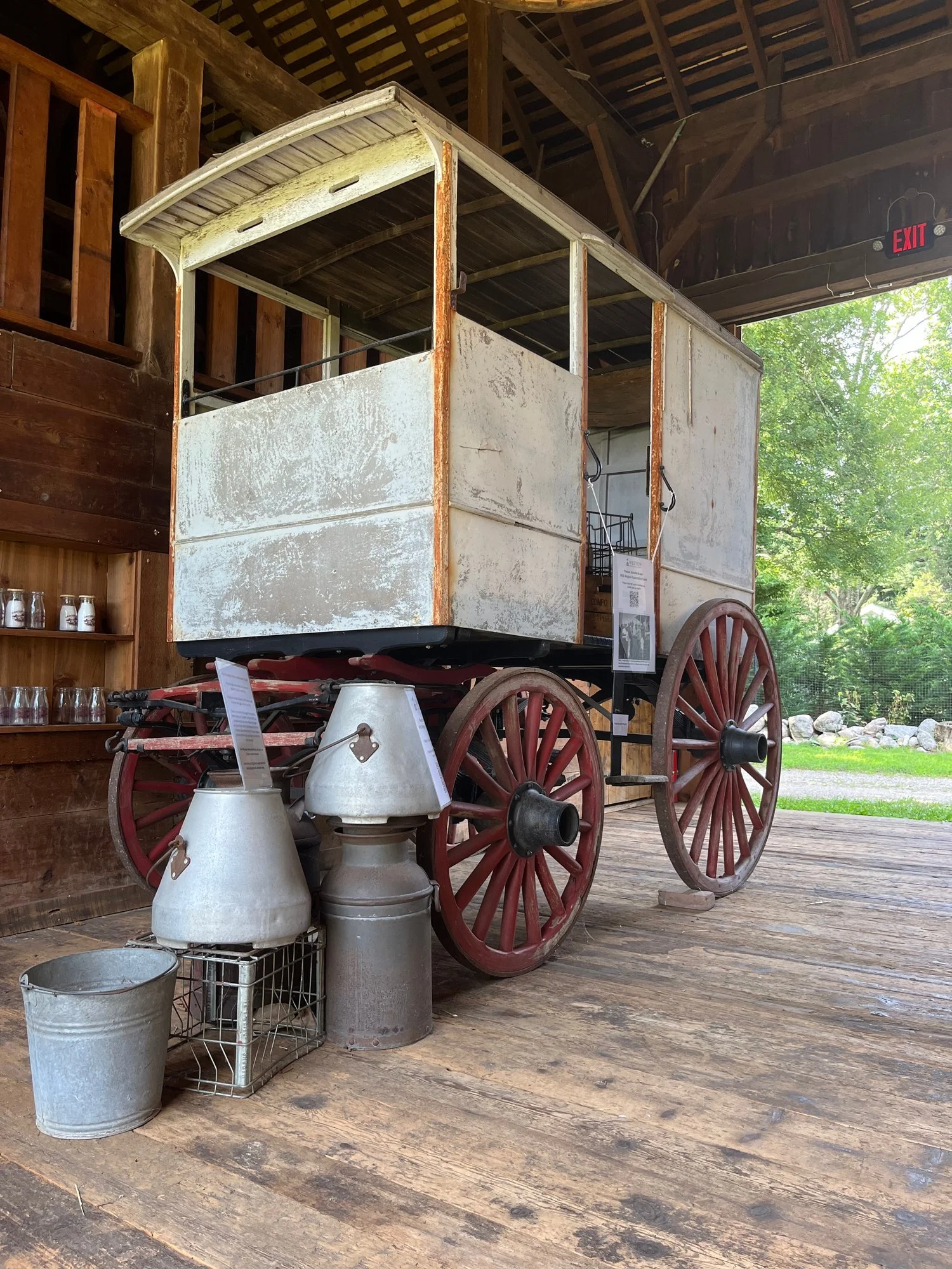 A horse-drawn delivery wagon with milk cans in the barn.