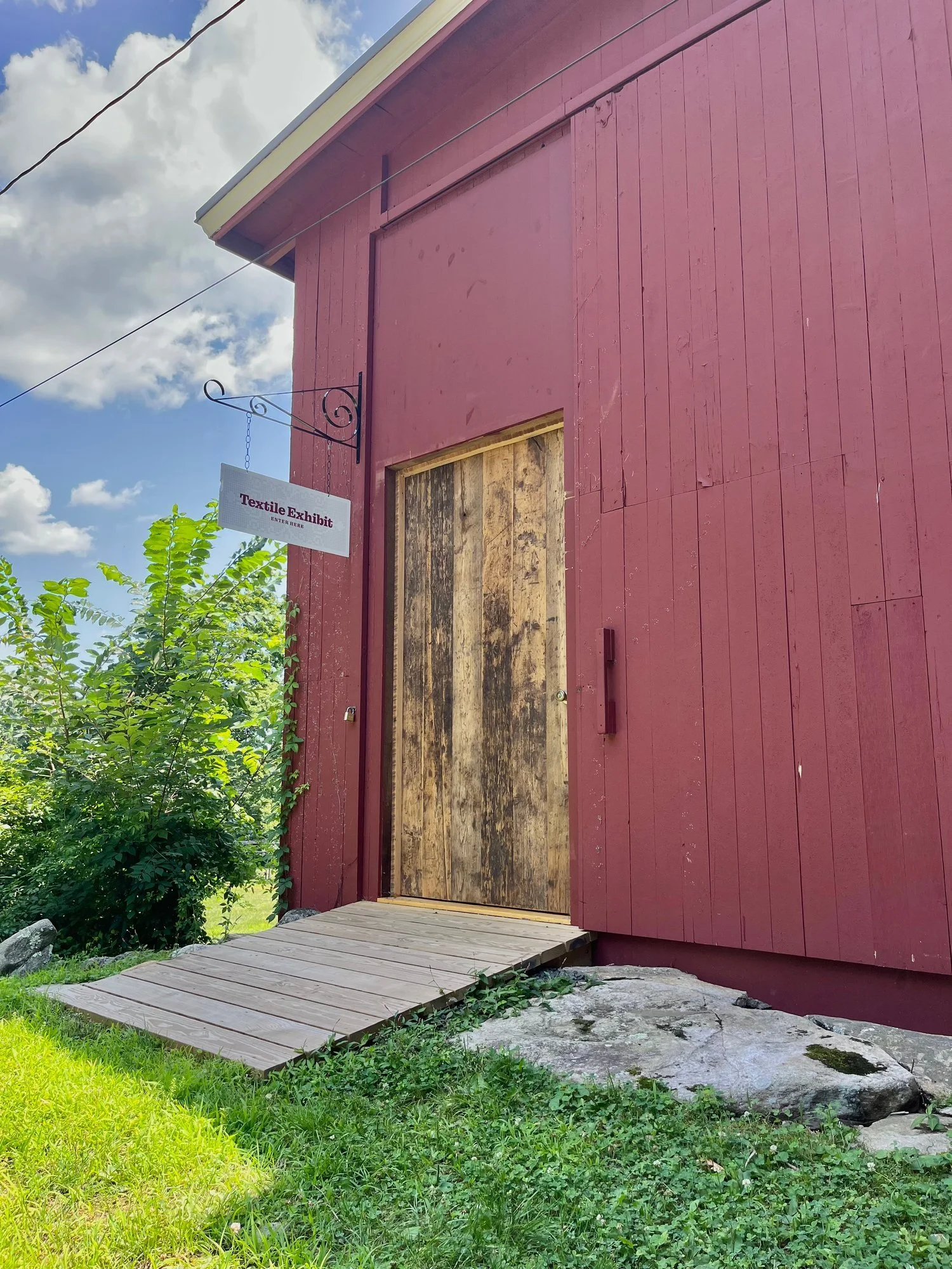 The barn's side door, with a hanging sign for the textile exhibit.