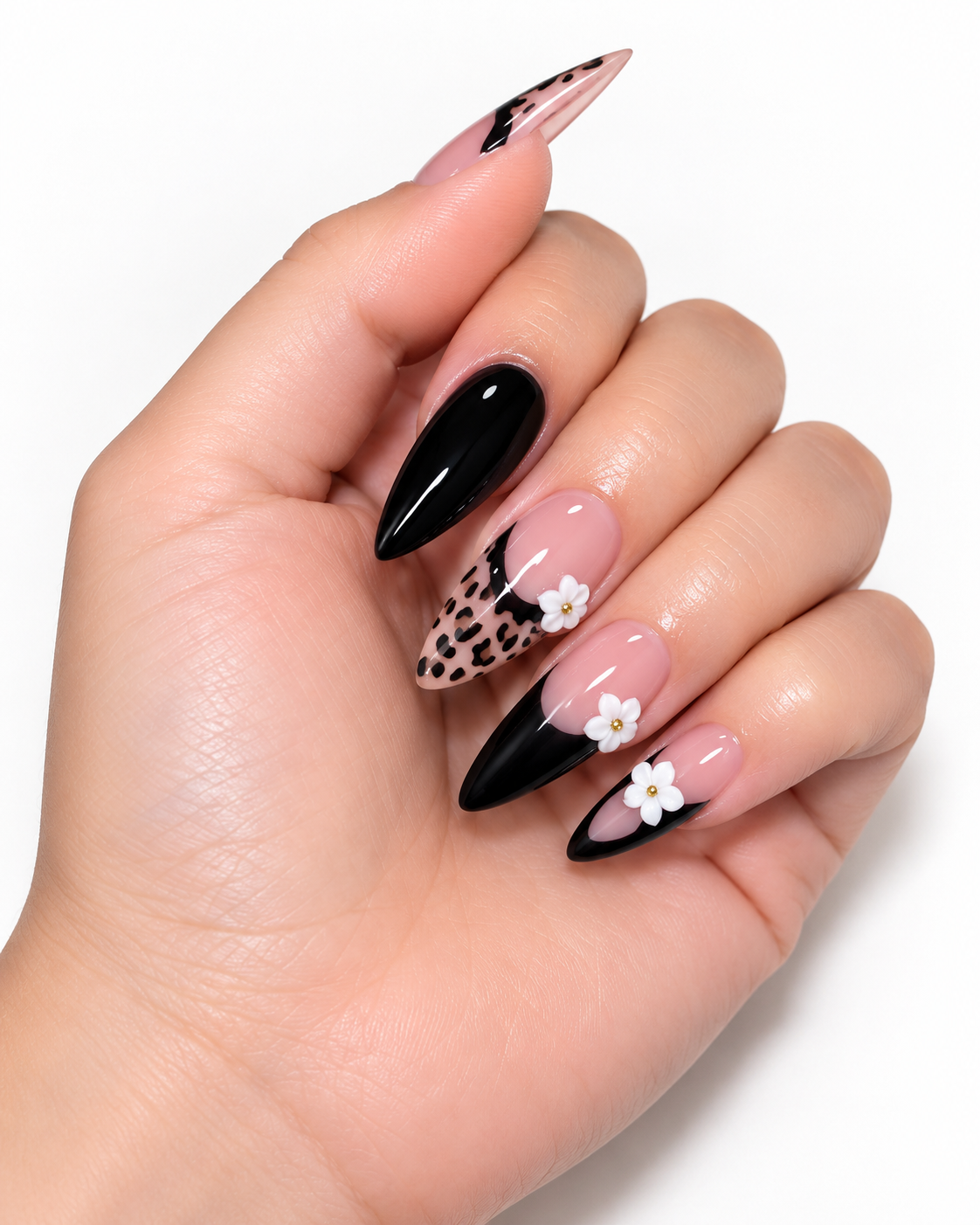 Manicure with long almond-shaped nails featuring black, animal print, and floral designs, with some nails painted solid black.