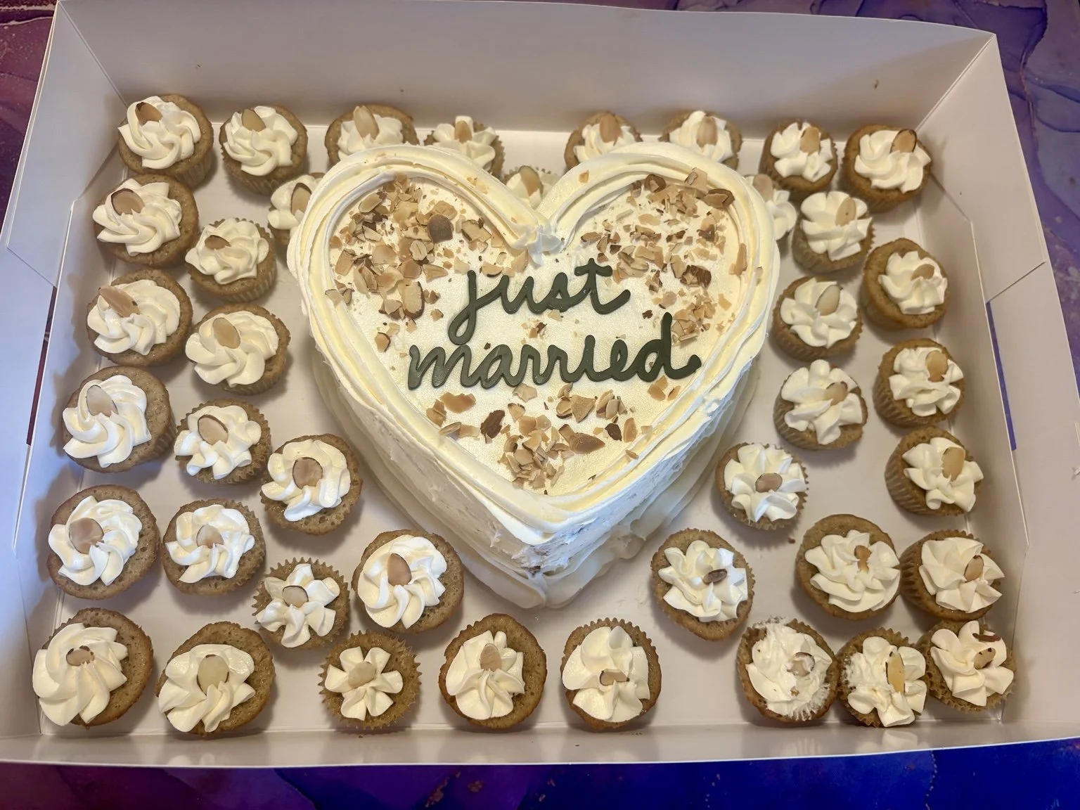 Heart-shaped celebration cake surrounded by mini cupcakes from Megan’s Bakes.