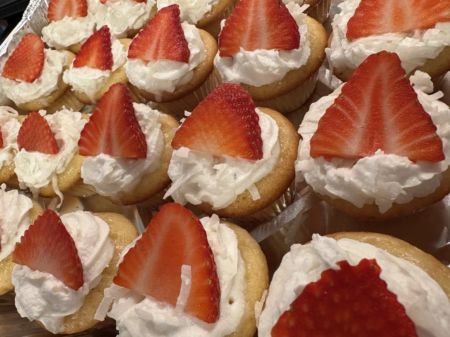 Cupcakes topped with frosting and fresh strawberries.