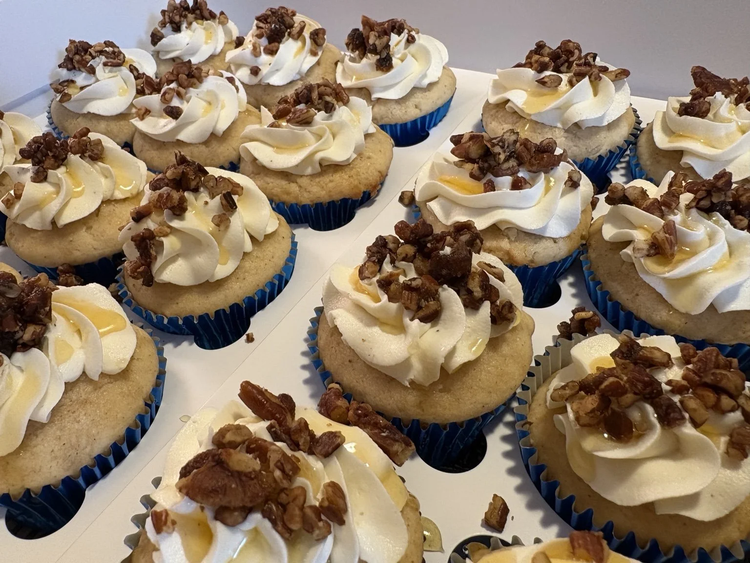 Cupcakes finished with swirled frosting and pecans.