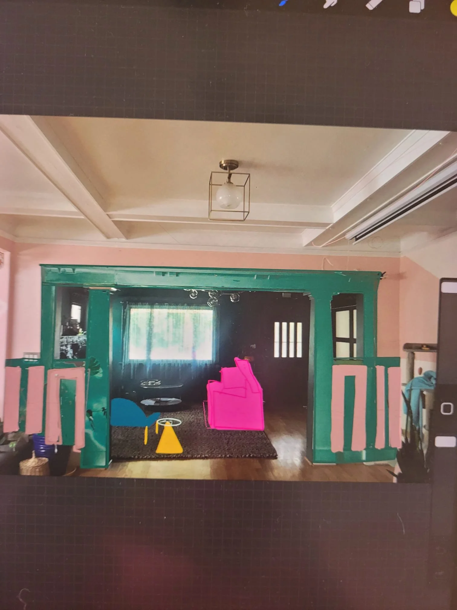 This is an indoor play area with various children's toys, including a yellow cone, a pink toy box, and a small blue slide inside a room with pink walls and a green-framed opening to another room.