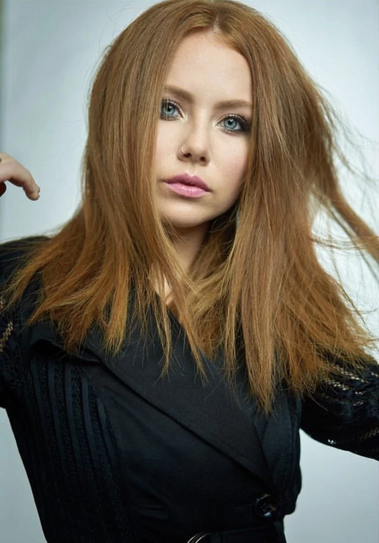 Long blonde balayage with a soft dark root, styled in waves