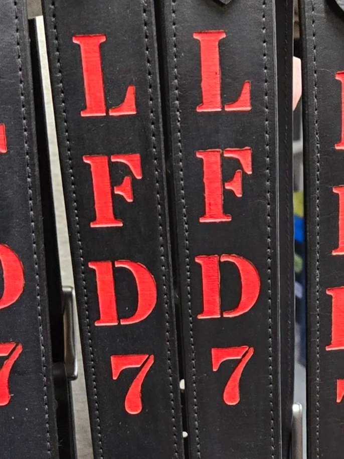 Close-up of custom red paint-filled engraving on black leather by Awl Star Leather.'