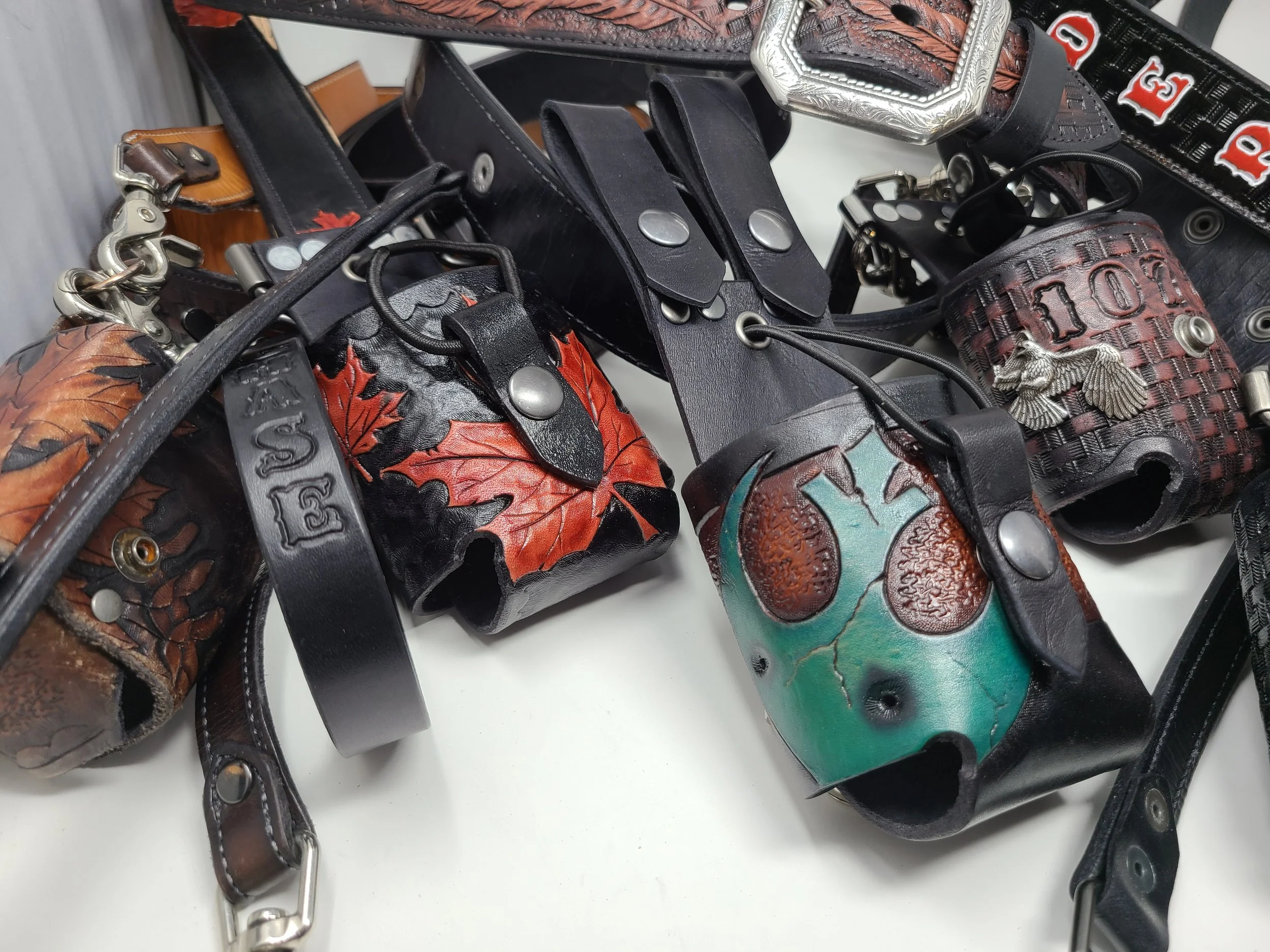 Collection of handcrafted Awl Star Leather radio harnesses and components in the workshop.