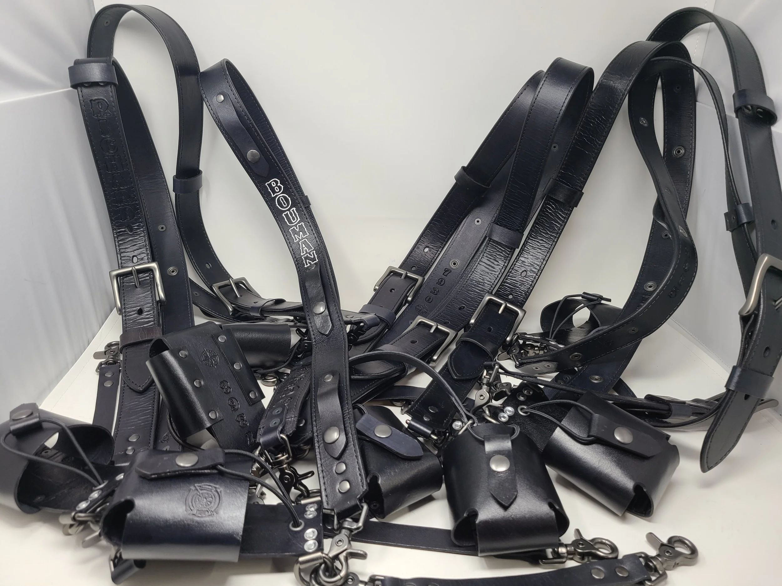 Collection of handcrafted Awl Star Leather radio harnesses with leather radio baskets and metal hardware.