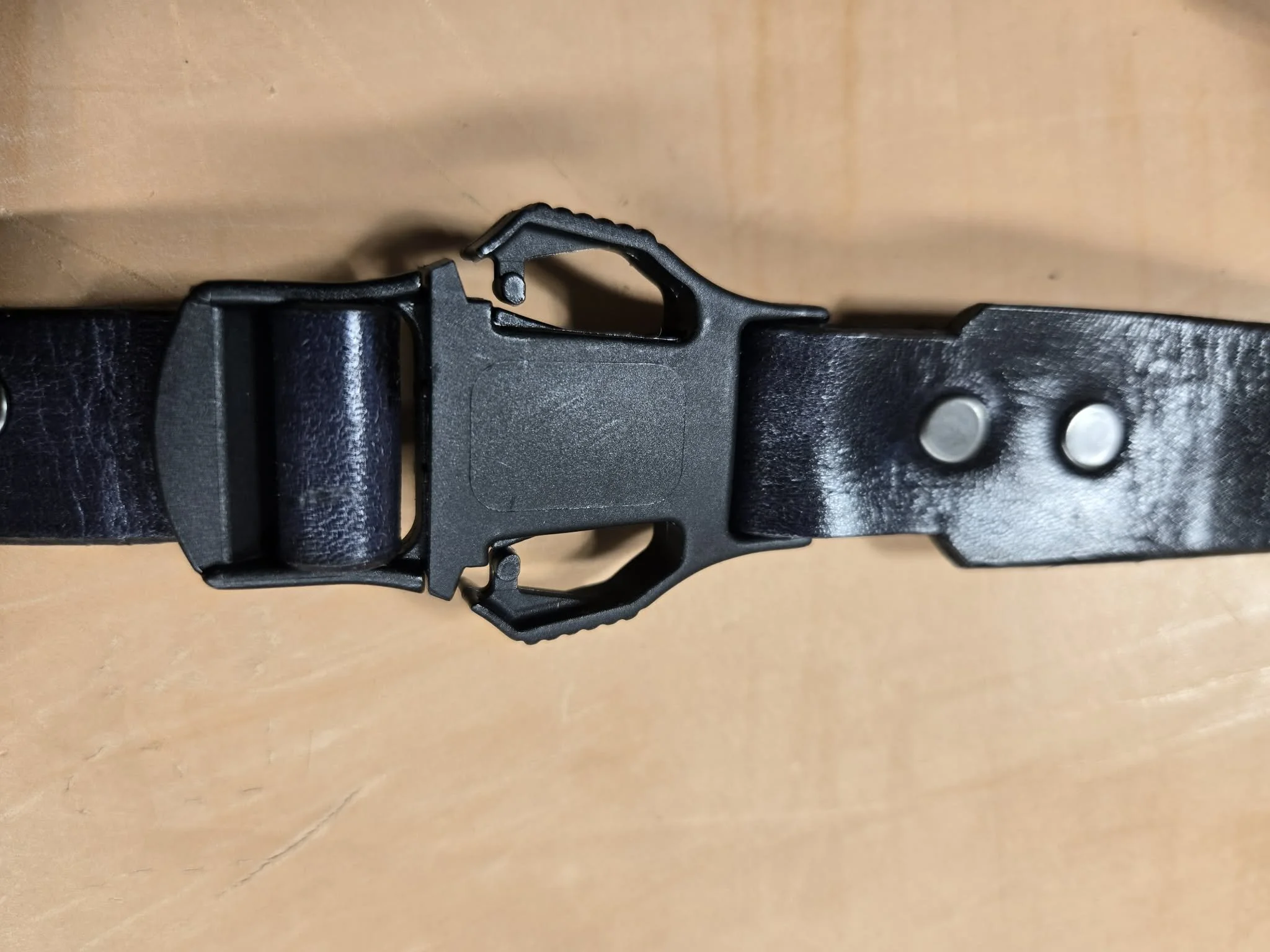 Close-up of an Awl Star Leather helmet chin strap showing the quick-release buckle and leather construction.