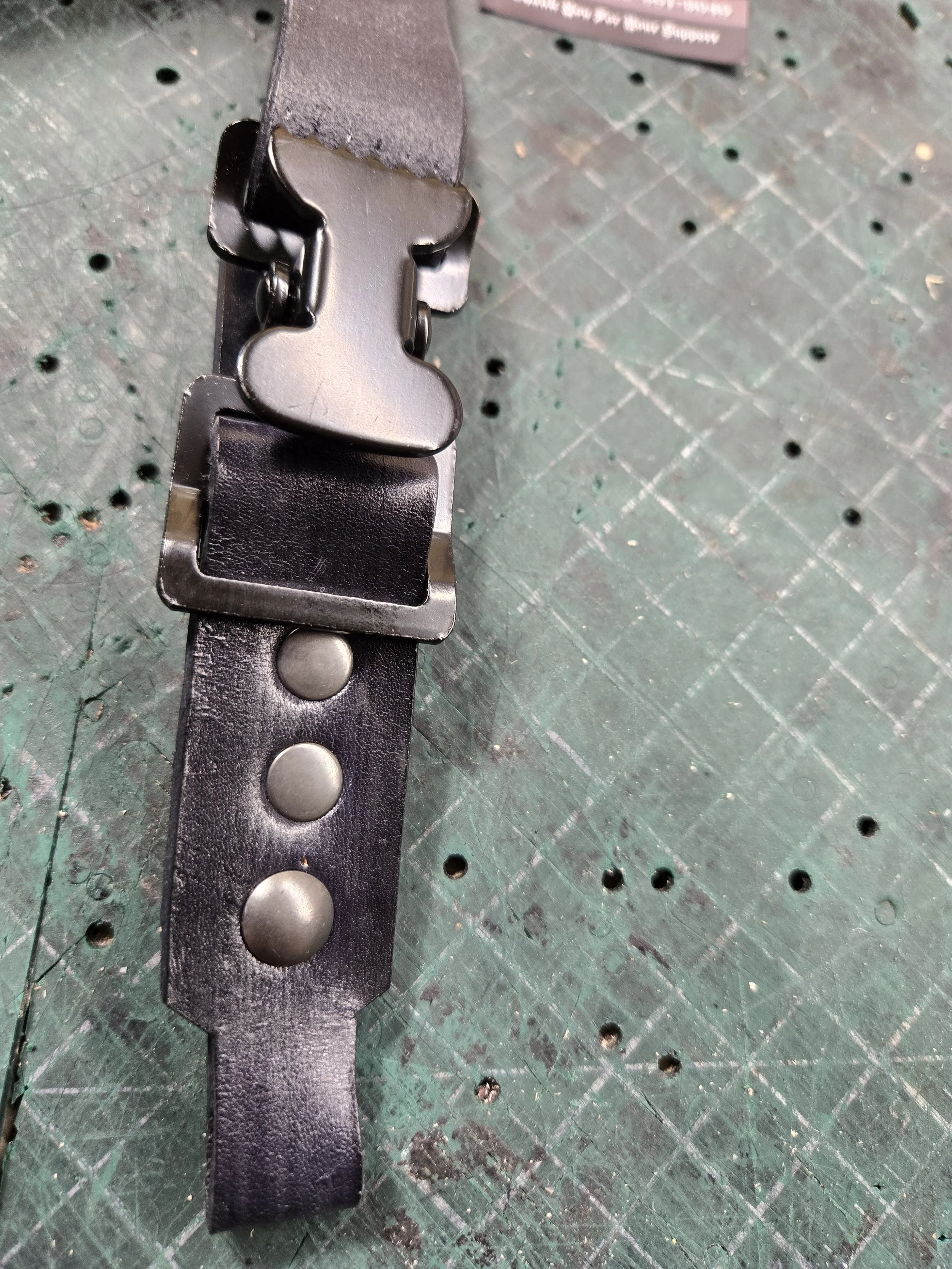 Close-up of an Awl Star Leather helmet chin strap showing the quick-release buckle and leather adjustment holes.