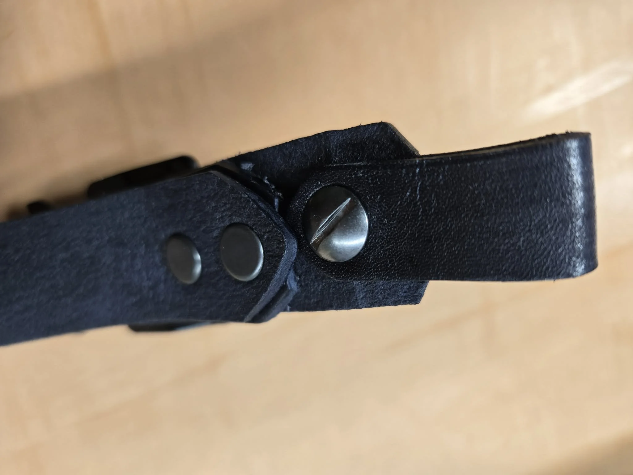 Close-up of the Chicago screw attachment on an Awl Star Leather leather firefighter helmet chin strap.