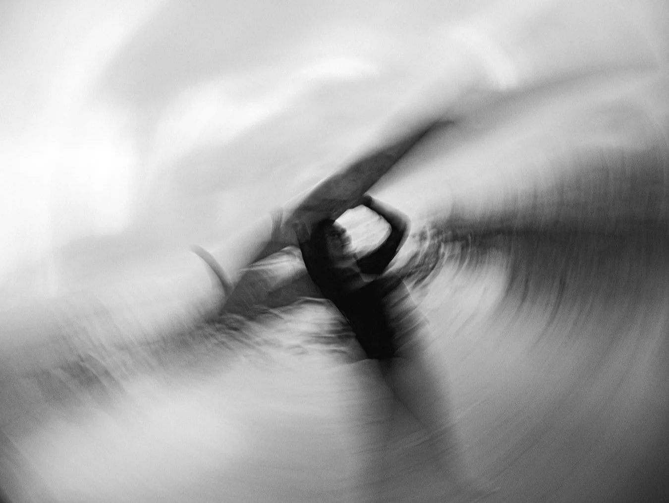 A person swimming underwater, doing a flip with arms raised above their head with blurred motion.