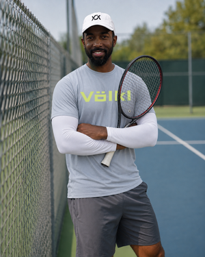 Abdul Jordan holding a tennis racquet by the court fence