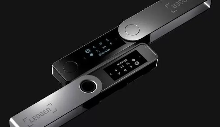 Two Ledger hardware cryptocurrency wallets, one silver and one black, on a black background.