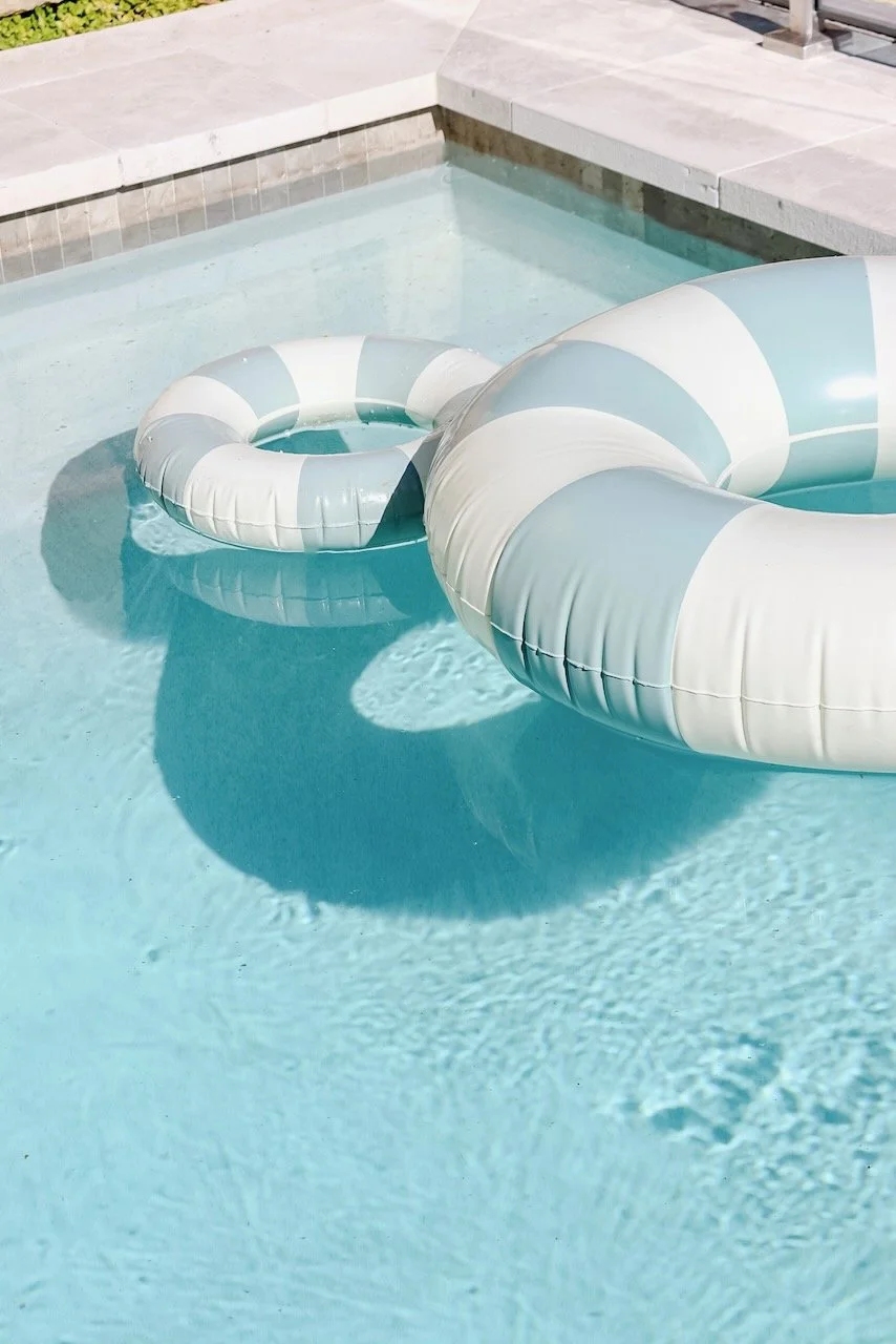 Clear swimming pool with a striped inflatable float in shades of blue and white.