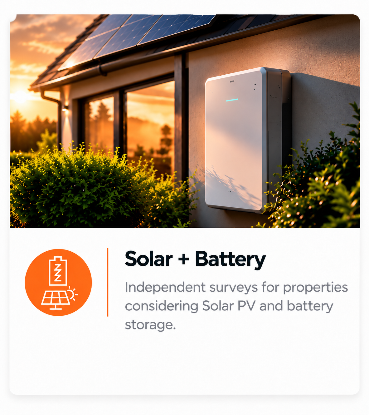 A solar battery storage unit mounted on the exterior wall of a house during sunset, with solar panels on the roof and green bushes in the foreground.