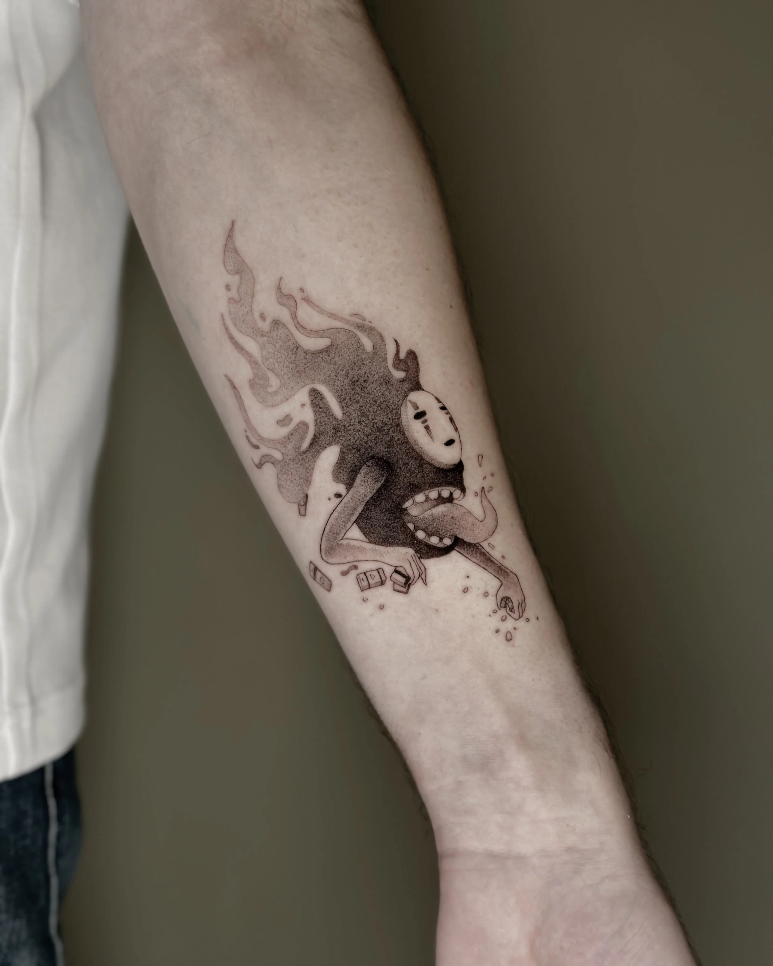 A person's forearm with a tattoo of the No Face from Studio Ghiblis's movie Spirited Away