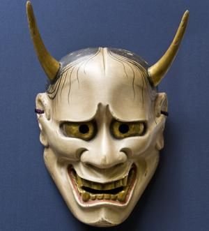 A traditional Japanese Hannya mask with human facial features, two horns, and metallic finish.