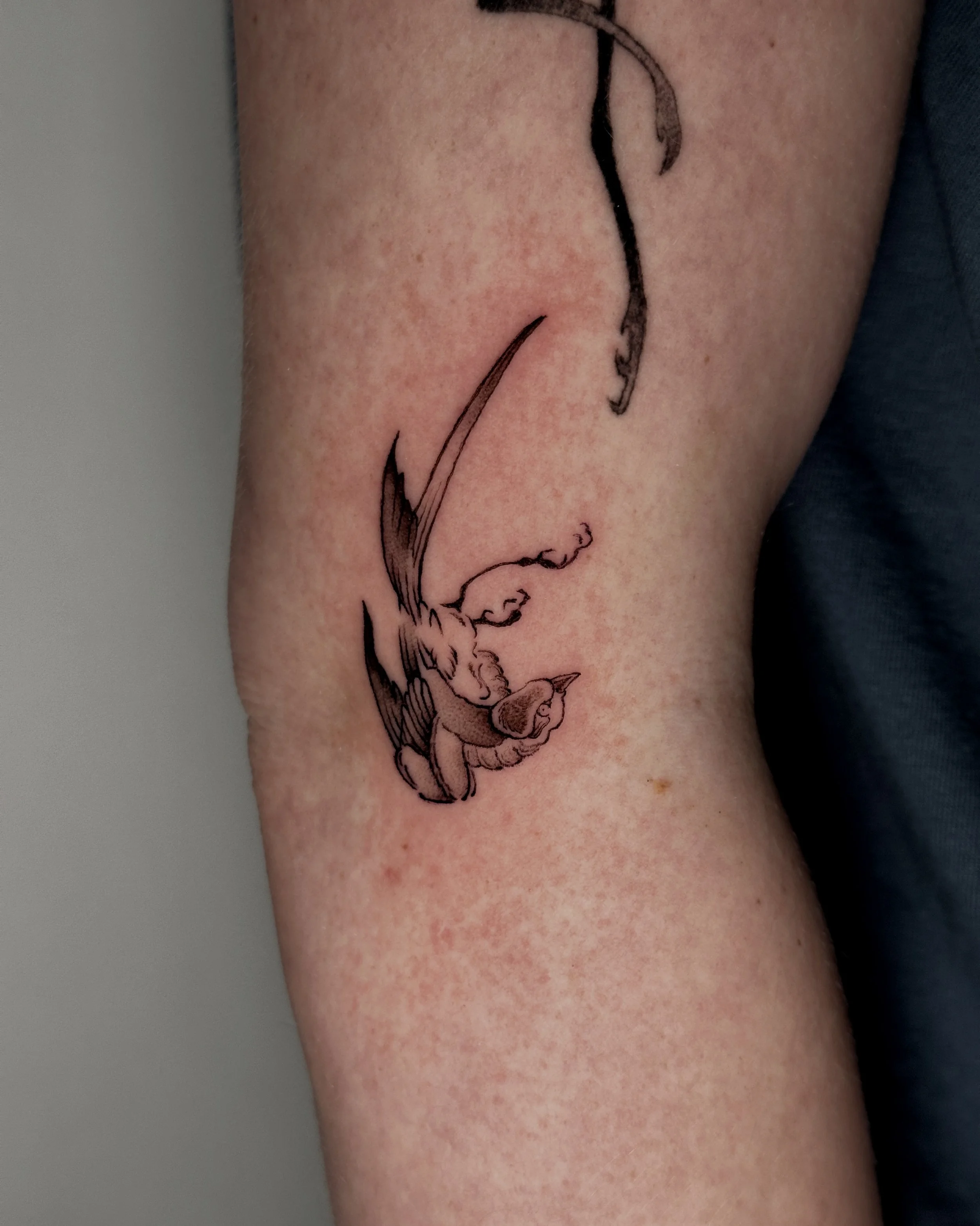 A tattoo of a detailed and artistic bird, likely a crane or sparrow, with long legs and a curved neck, on a person's skin. in a traditional japanese painting style