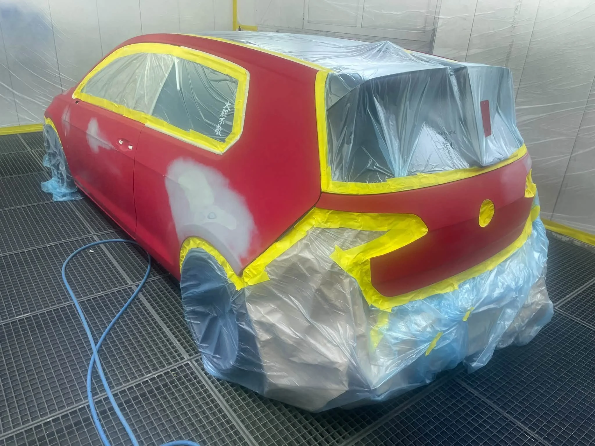 Ein Auto, das in einer Lackierkabine grau grundiert wird, um es für den Lackiervorgang vorzubereiten.