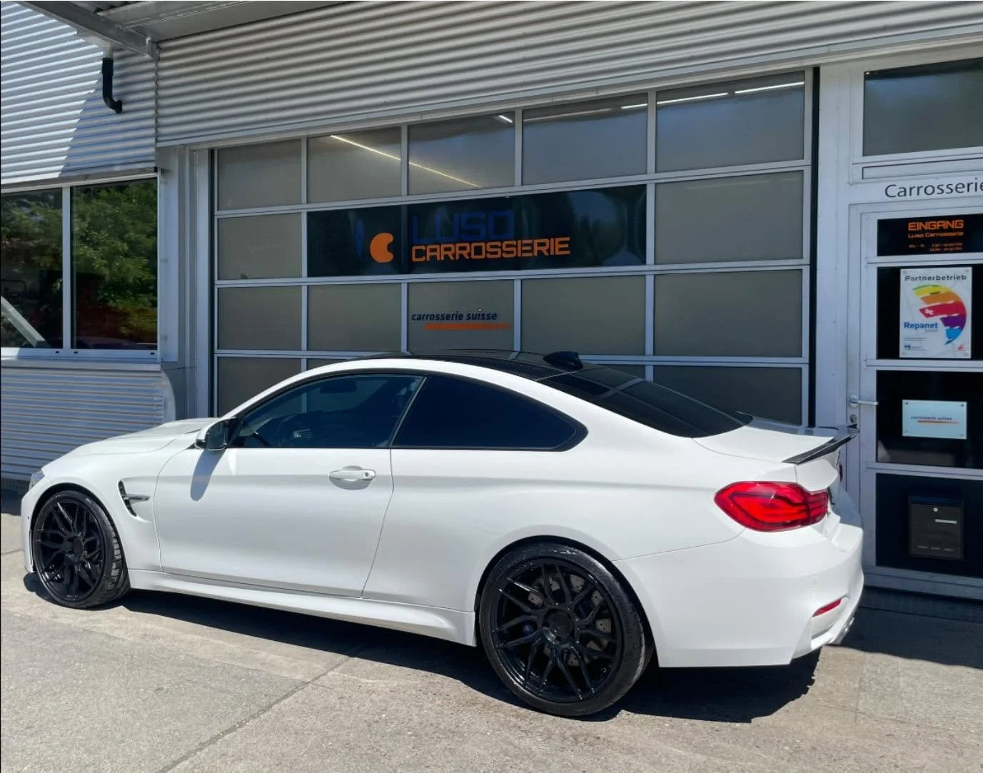 Weißer Sportwagen vor einer Werkstatt, die Carrosserieservices anbietet.