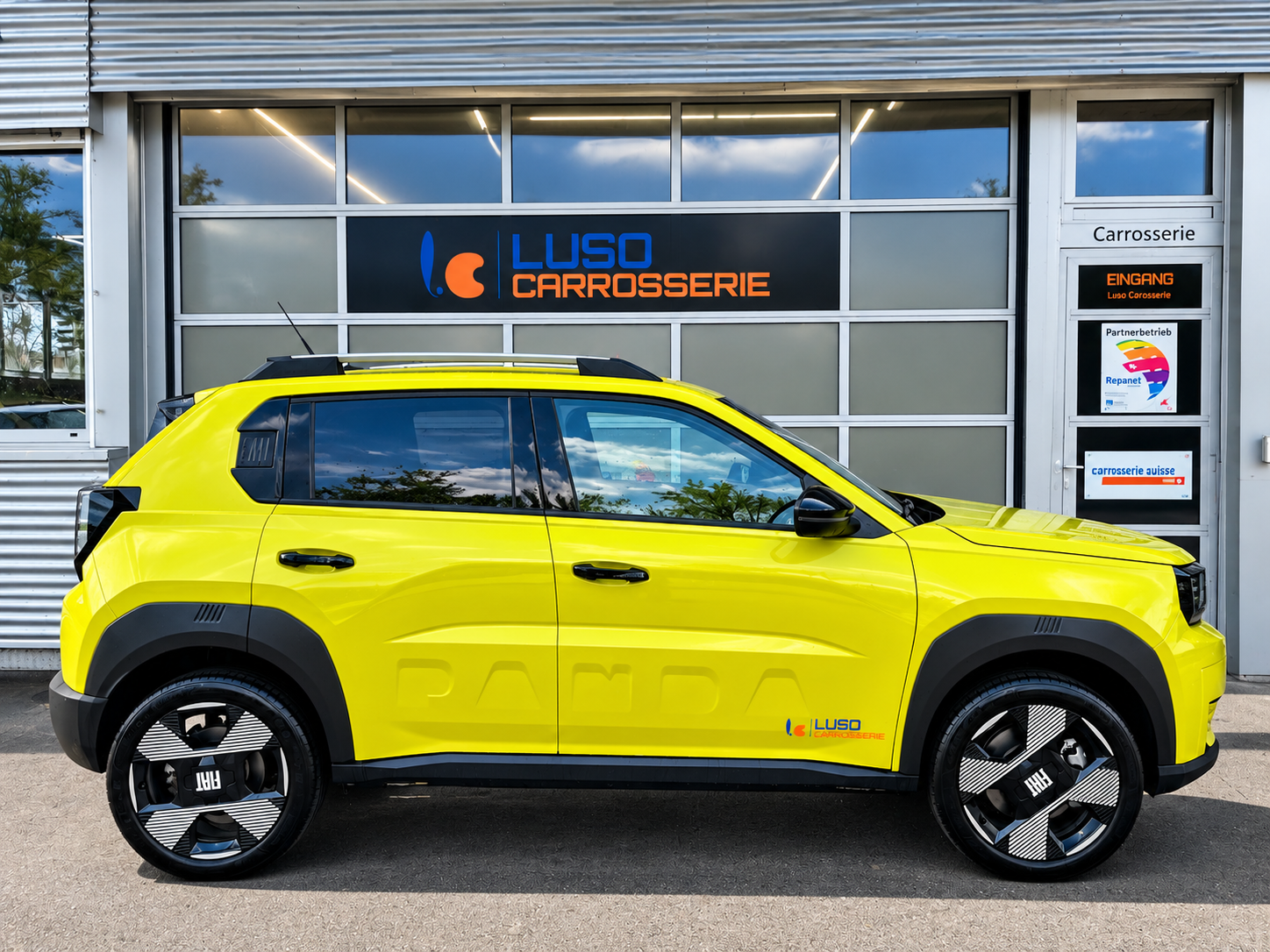 Ein gelbes Auto vor einer Werkstatttür mit dem Schild 'Luso Carrosserie', das ein Auto-Repair-Geschäft ist.