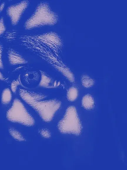 Rostro humano en tonos azules, con énfasis en un ojo, efecto de doble exposición y una sombra con textura de tejido entrelazado