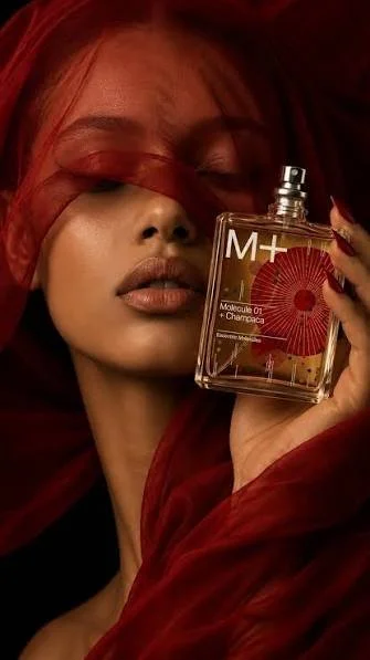 A woman with red hair holding a perfume bottle labeled 'M+' and 'Molecule 01 + Chemistry' close to her face.