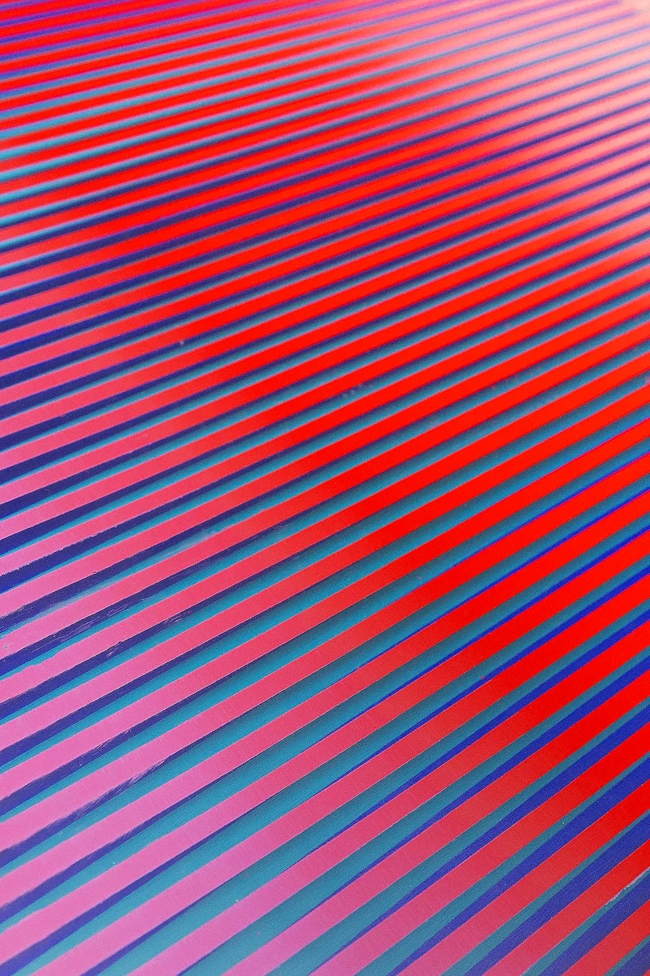 Close-up of a colorful textured surface with diagonal stripes in red, purple, and blue.