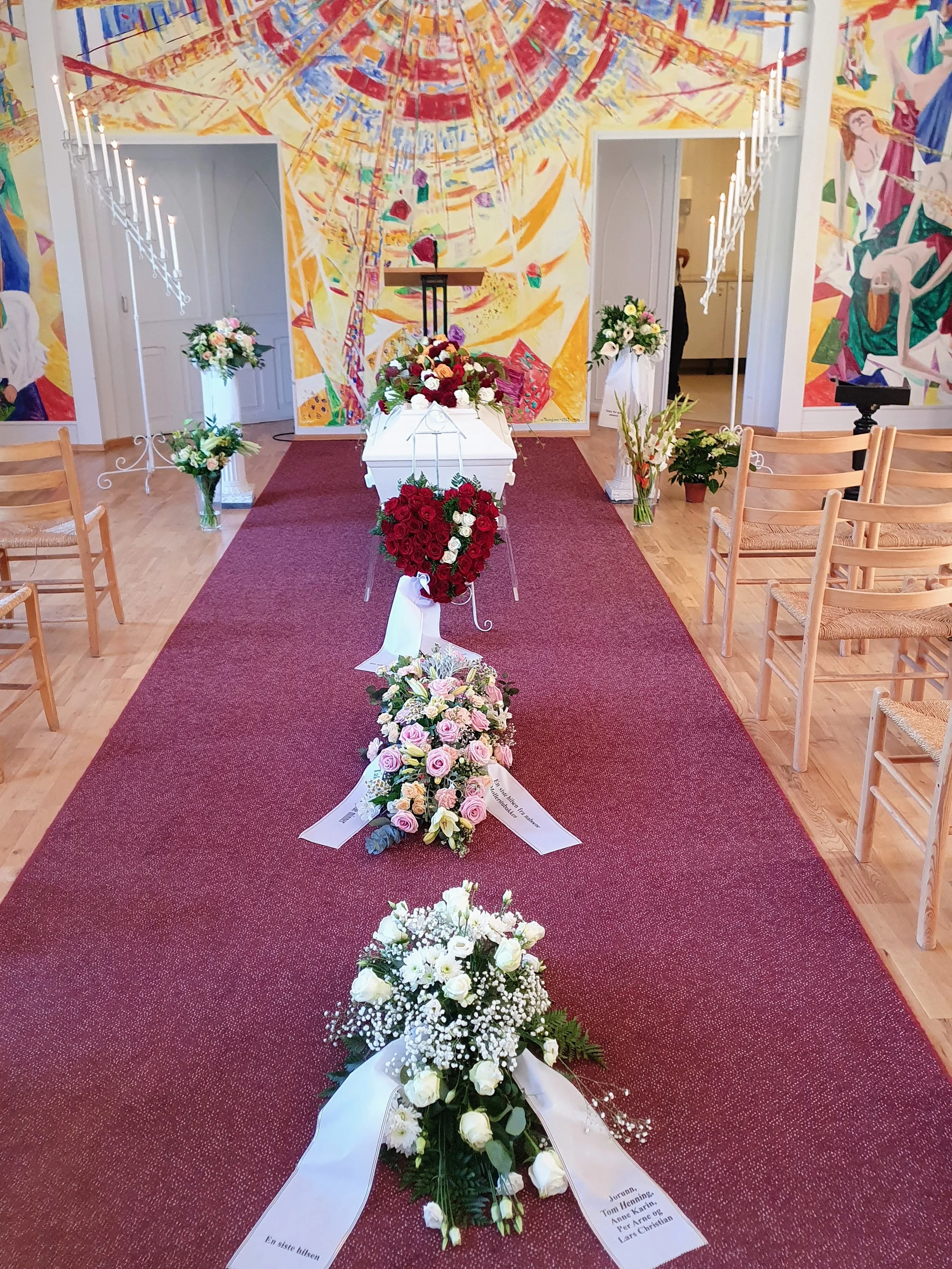 Minnesamling med blomster og en kiste, gode ønsker og hilsen med navnene til de avdøde, i en kirke.
